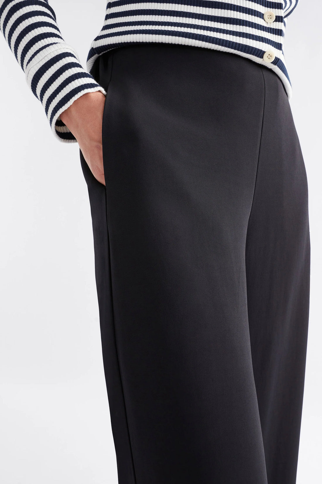 woman hand in the pocket wearing white and black stripe top and black pants