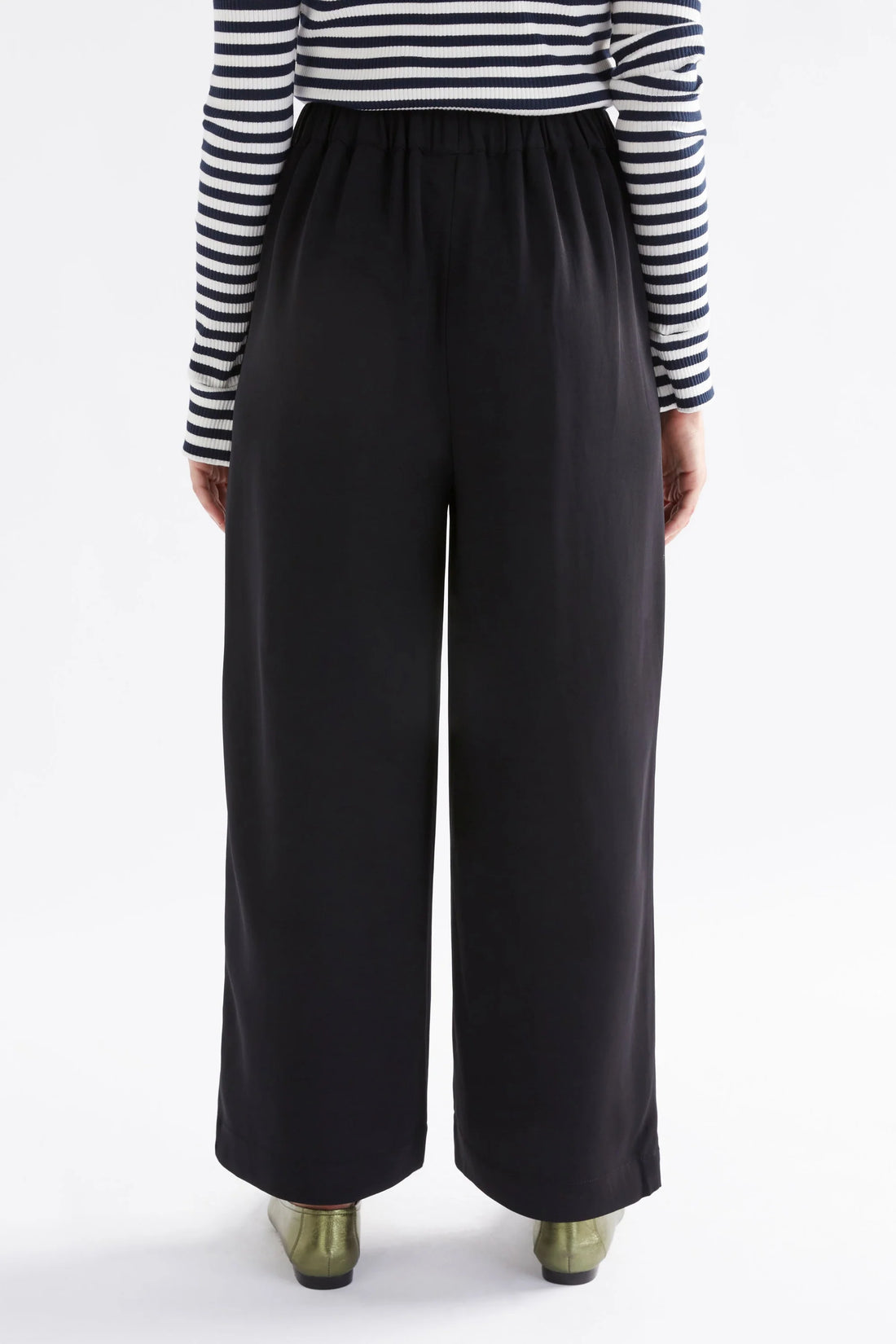 woman facing the back wearing white and black stripe top and black pants
