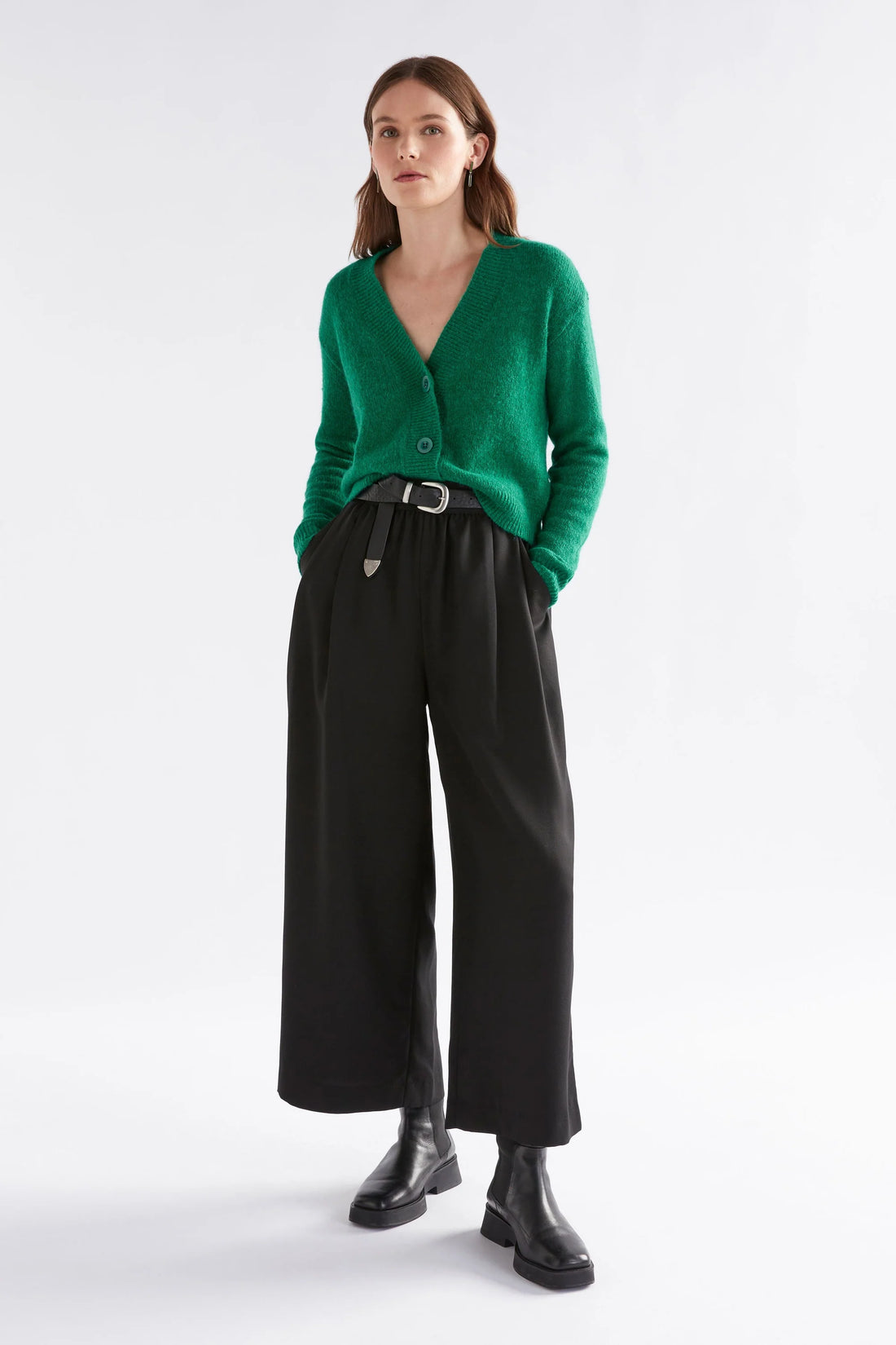 Woman wearing Daaru Cardigan in Milan Green and black pants
