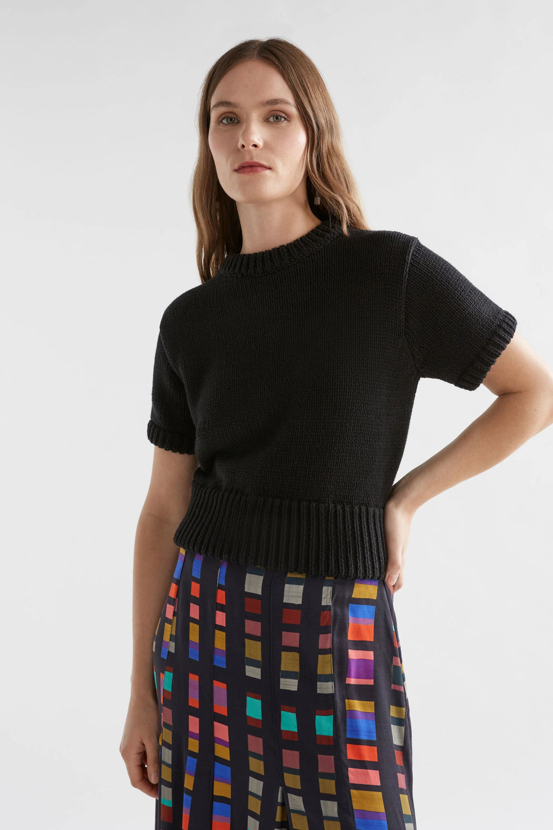 Woman wearing black luft knit top and multi-coloured skirt