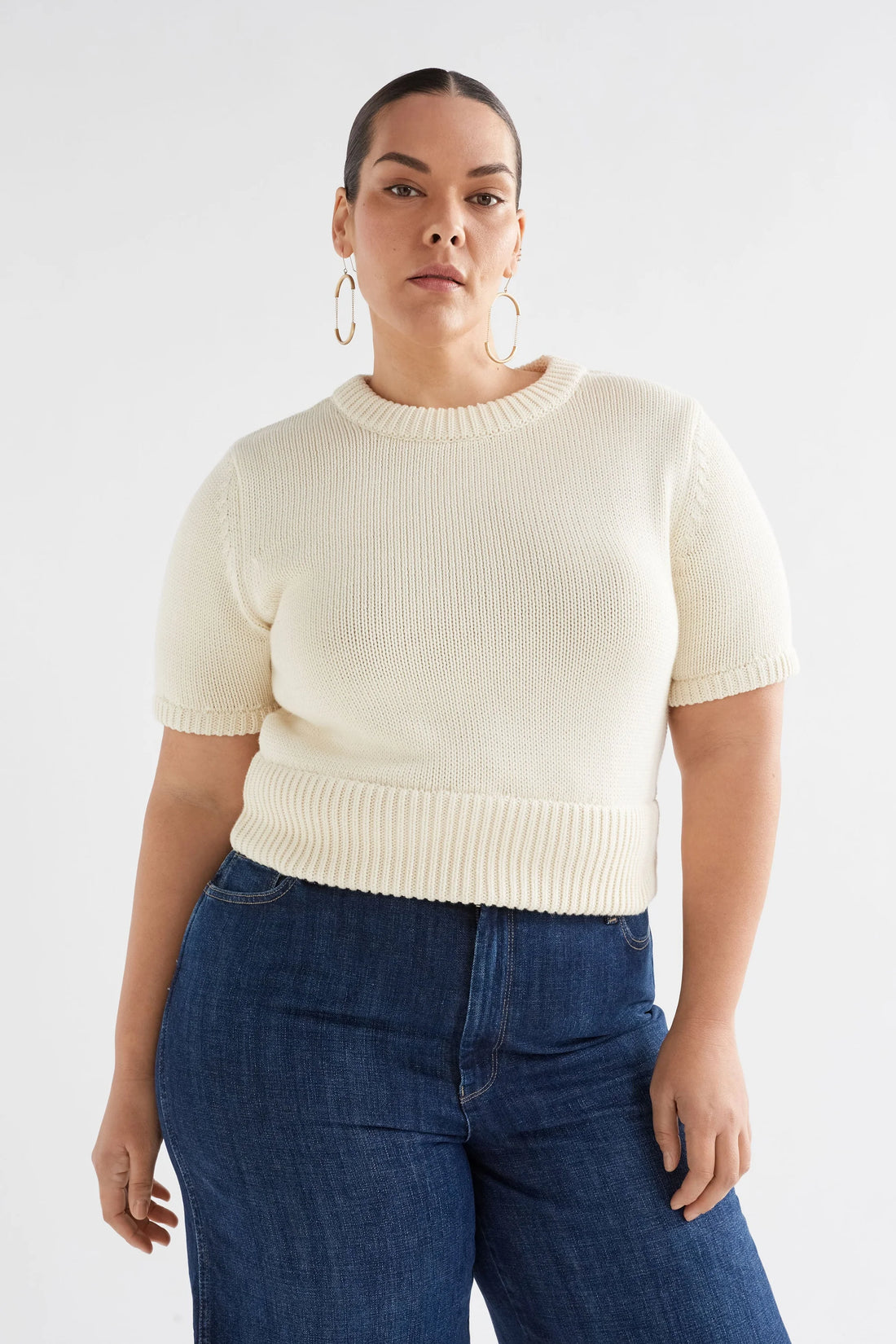 plus size woman wearing Luft Knit Top in white and denim pants