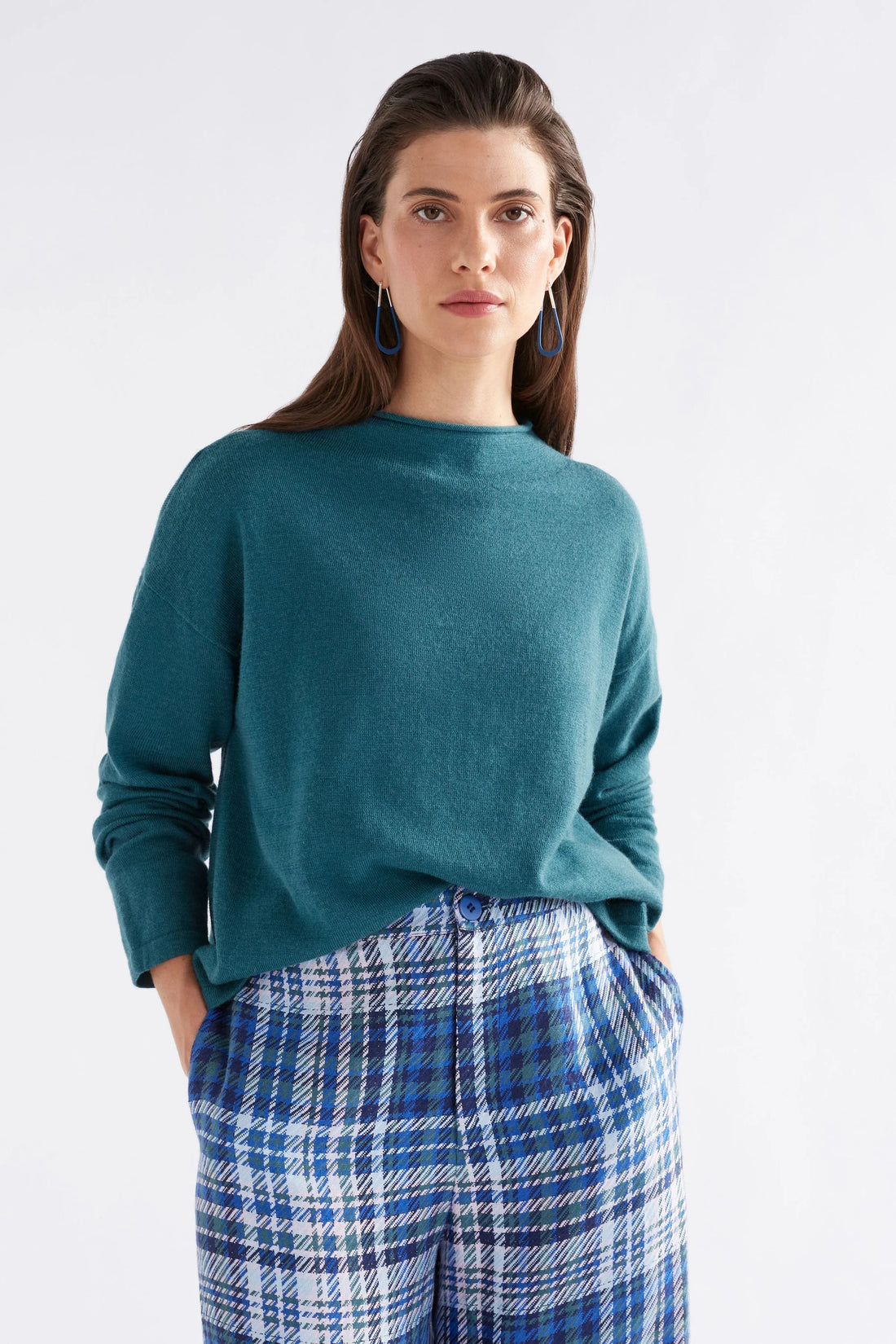 Woman wearing Pirata Sweater in Sea Moss colour and plaid blue pants