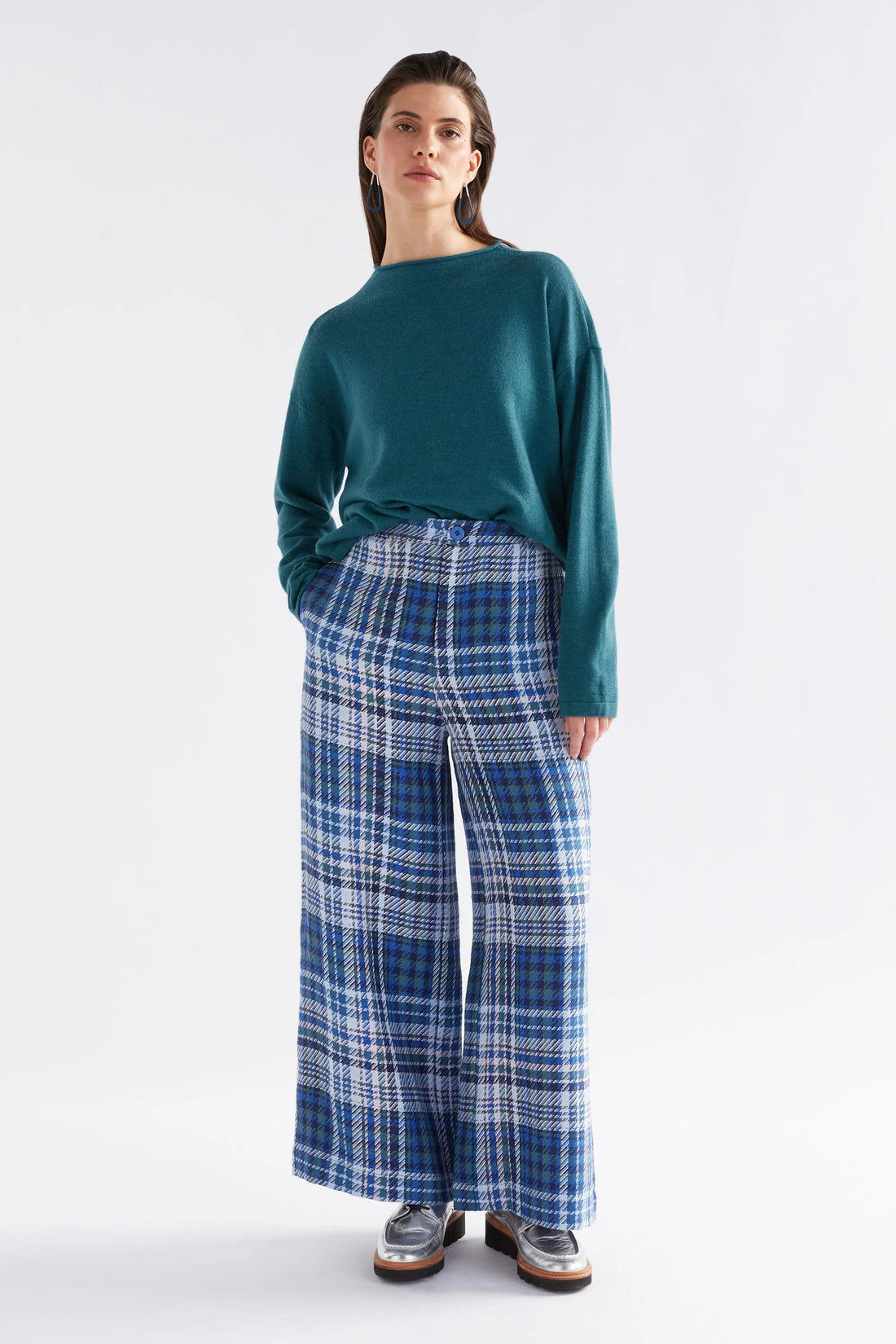 Woman wearing Pirata Sweater in Sea Moss colour and plaid blue pants