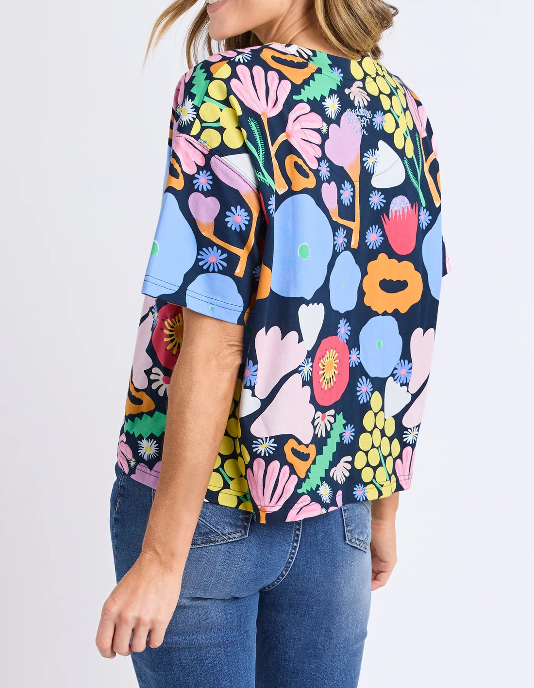 Woman wearing Flower Medley Tee - Multi and denim pants back view