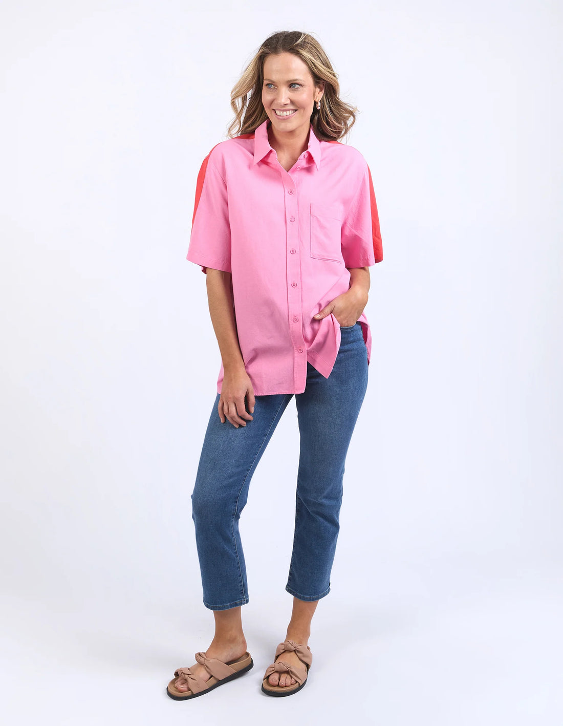 standing woman wearing elm lifestyle frances stripe in strawberry pink, denim pants, and brown slippers