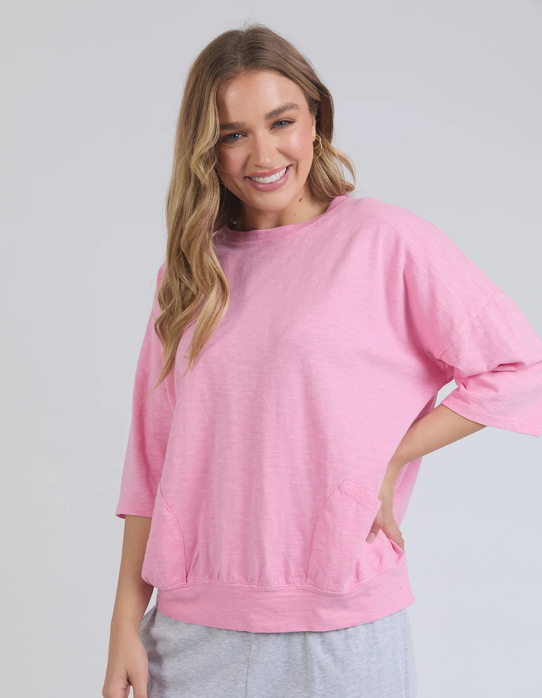 Woman wearing elm lifestyle sweat in strawberry pink and grey pants