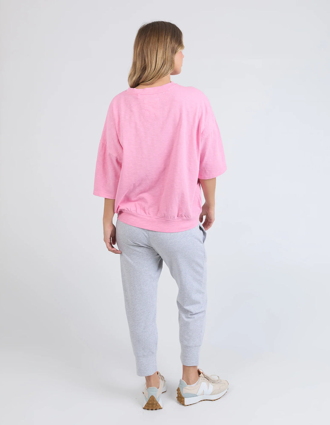 woman facing the back wearing elm lifestyle mazie sweat in strawberry pink, grey pants, rubber shoes