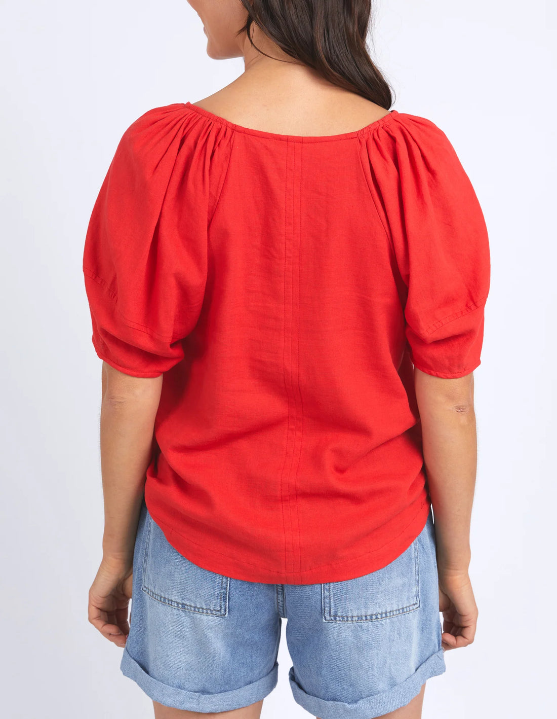 woman facing the back wearing elm lifestyle the grove top in bittersweet red, denim shorts