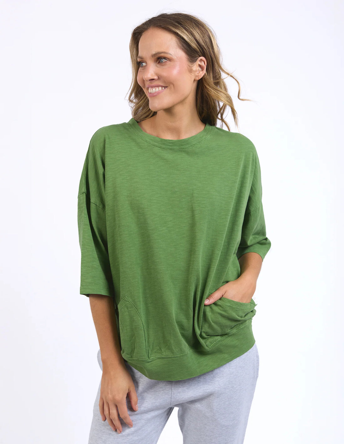 Woman wearing Cedar green Mazie Sweat and grey pants