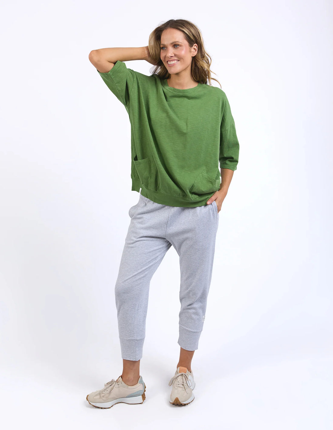 Woman wearing Cedar green Mazie Sweat and grey pants