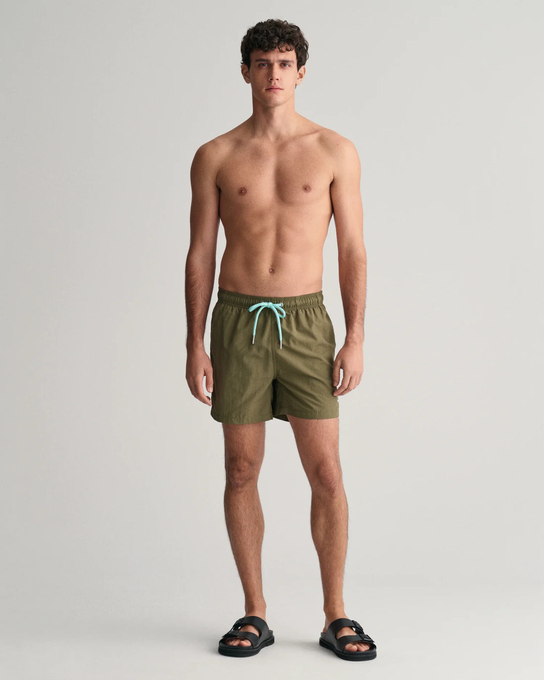 man wearing gant basic swim shorts juniper green and black slip on