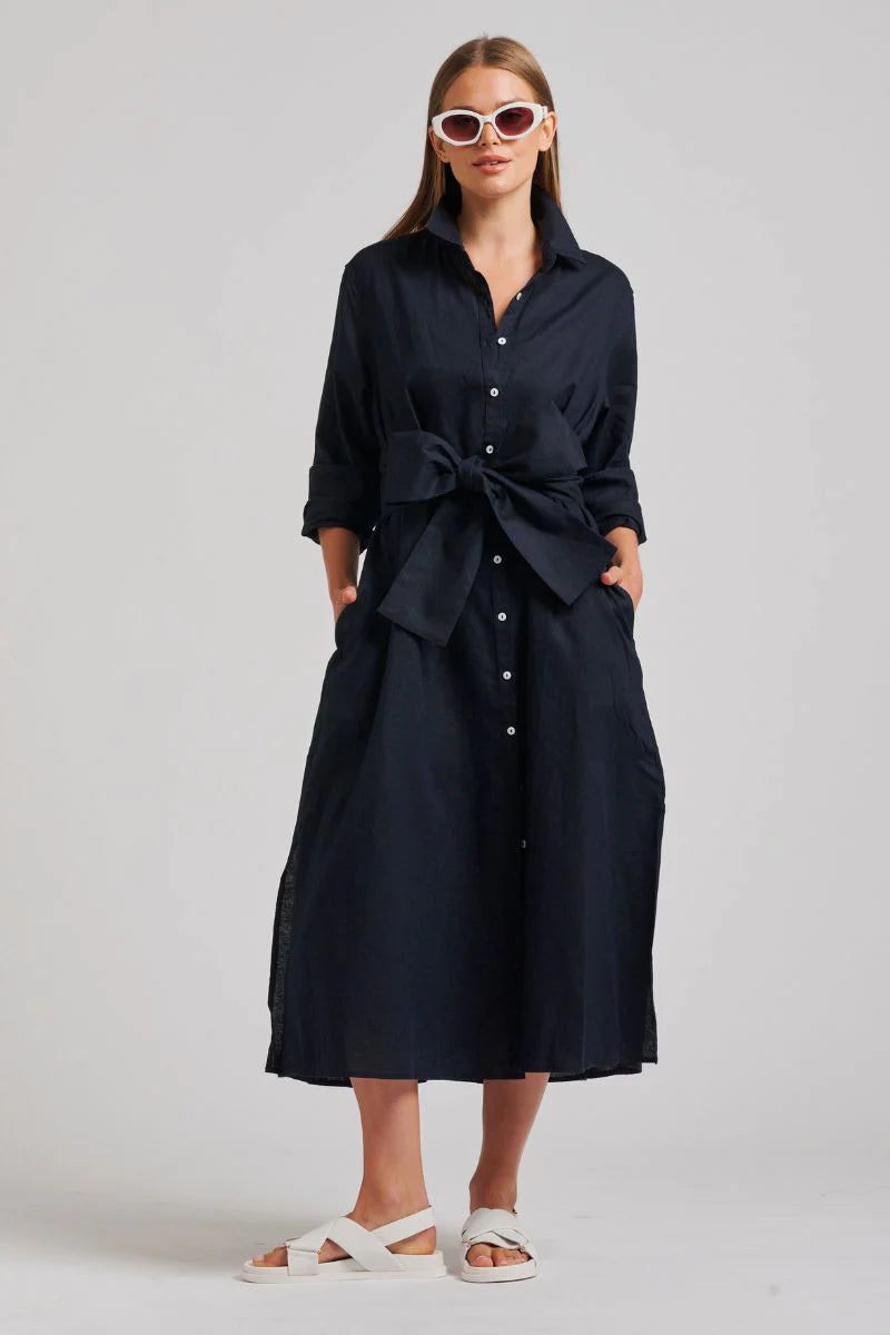 woman wearing white shades, white slippers, and the shirty the luna oversized linen long shirtdress french navy with belt in ribbon style