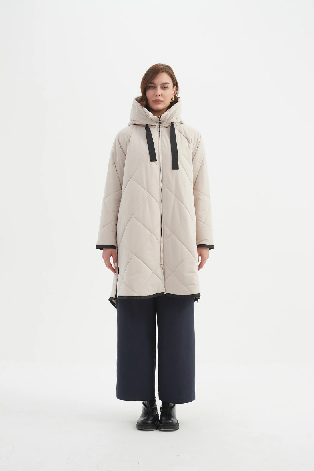 Woman wearing navy blue top and navy pants with Zip Hem Winter Coat - Cream