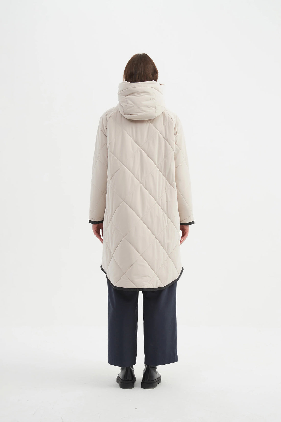 Woman wearing navy blue top and navy pants with Zip Hem Winter Coat - Cream facing the back