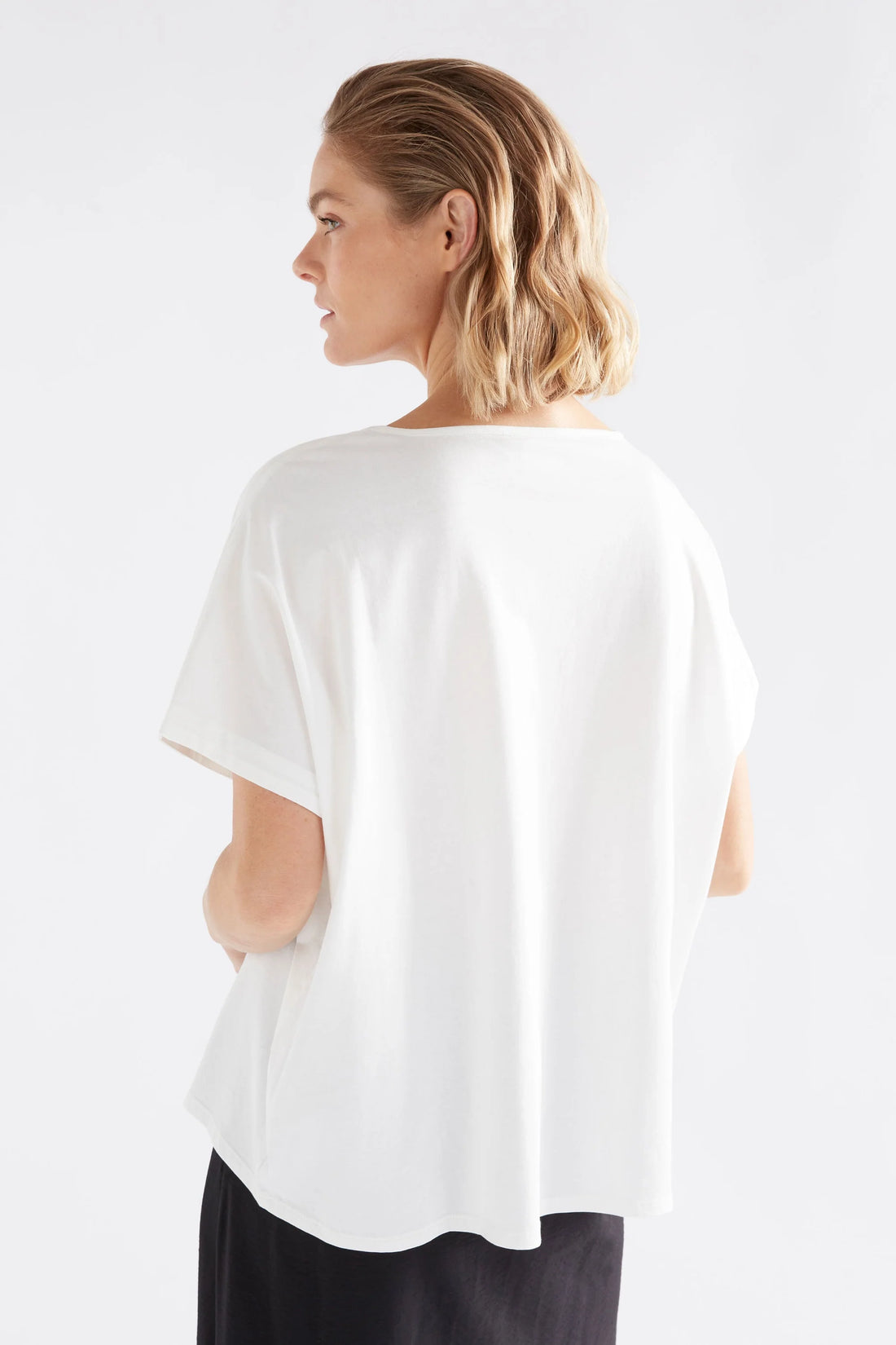 woman facing the back wearing black skirt and elk bruk tee with black tropea placement print