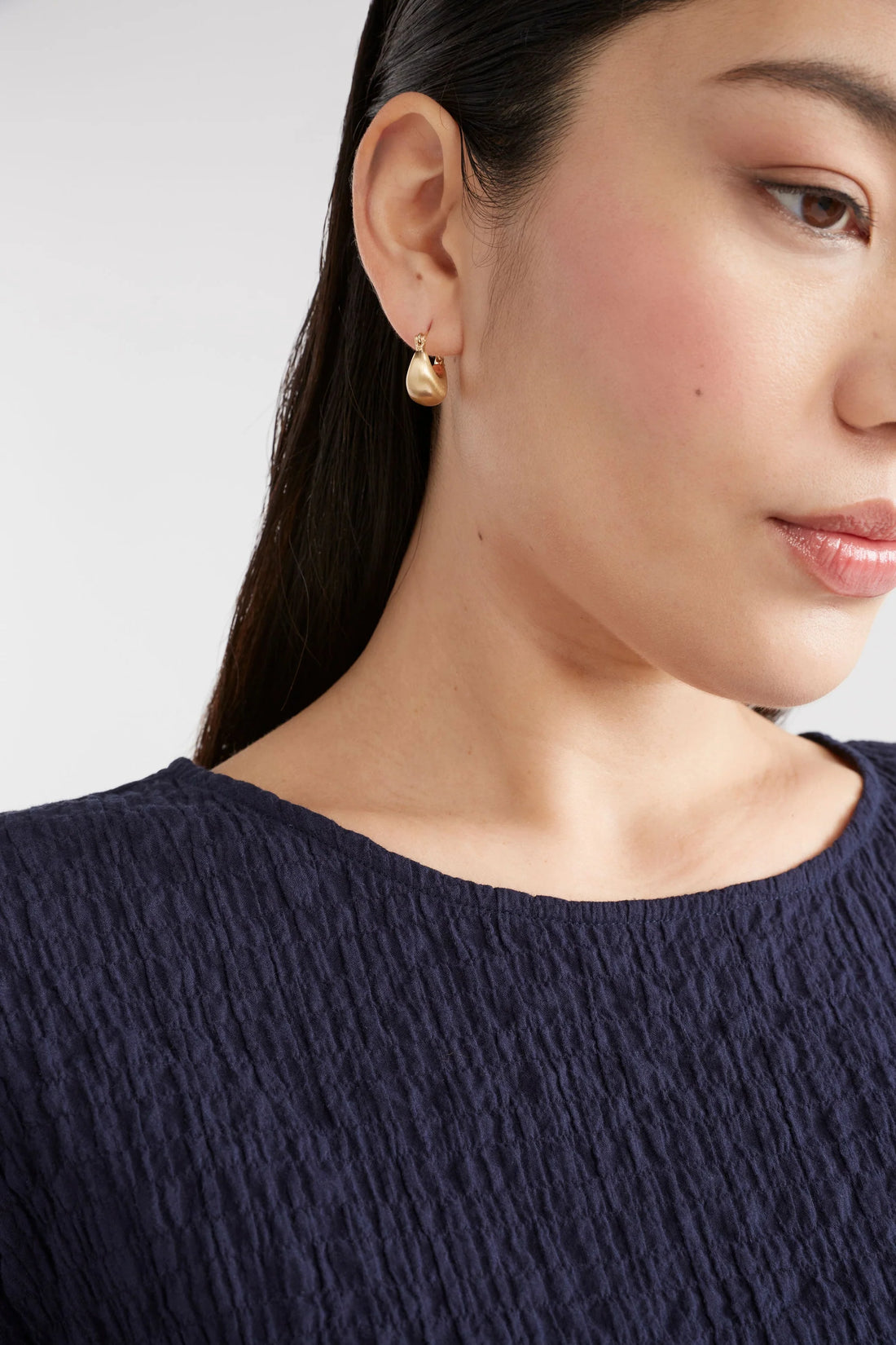 woman wearing navy blue shirt and elk ellik short hoop earring gold
