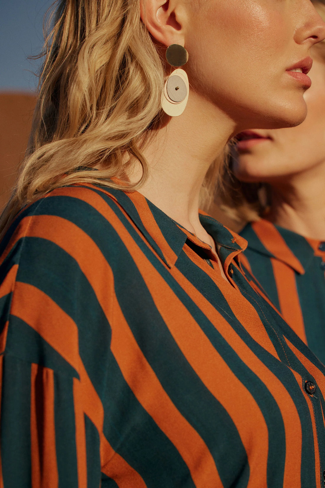 woman waring orange and colour dark colour stirp and elk orb earring gold