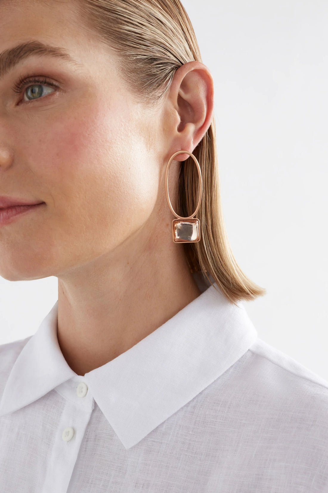 woman wearing white top and elk stal drop earring champagne