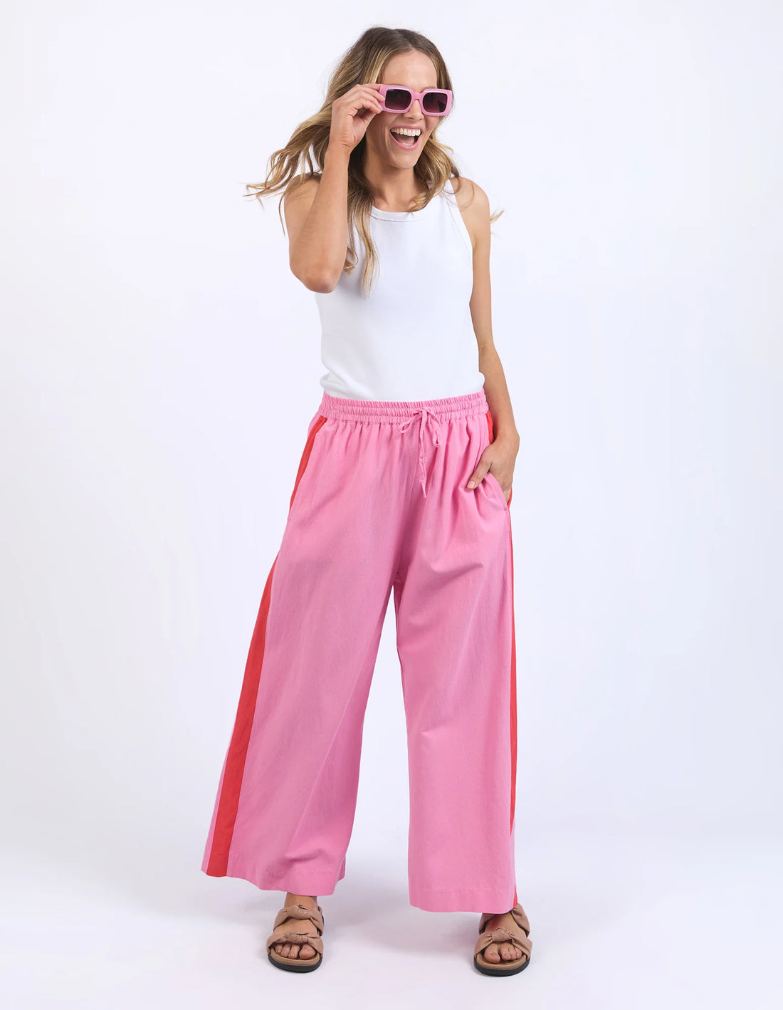 woman standing wearing pink shades, white sleeveless top and elm lifestyle frances stripe pant strawberry