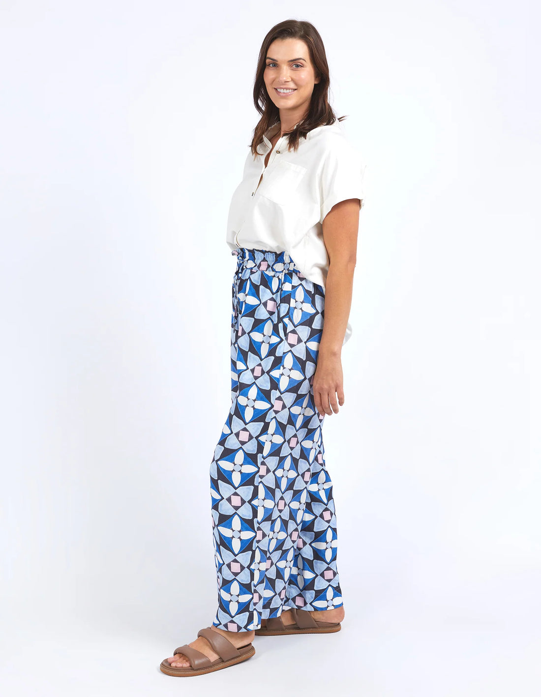 woman wearing white top, elm lifestyle painted tile pant geo print, and brown slippers