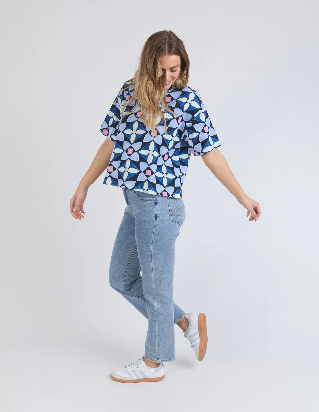 woman wearing elm lifestyle printed tile tee geo print, denim pants, and white shoes