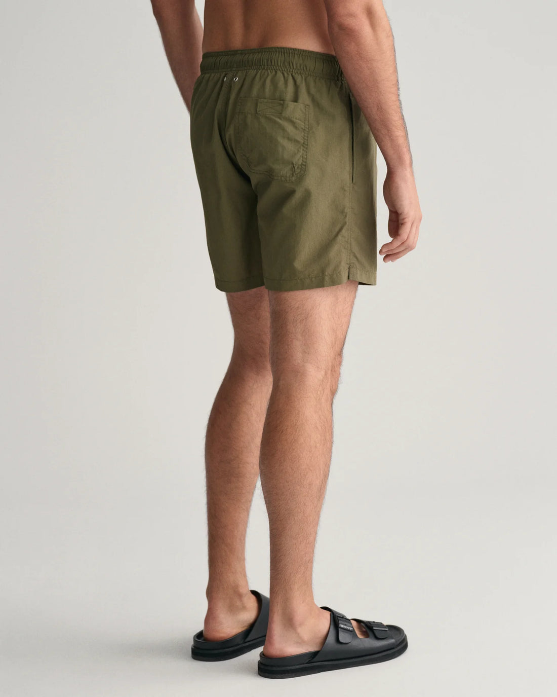 man wearing gant basic swim shorts juniper green and black slip on