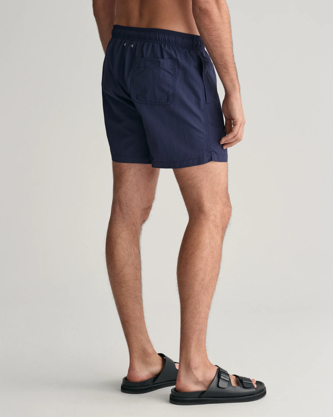 man wearing gant basic swim shorts in marine and black slip on