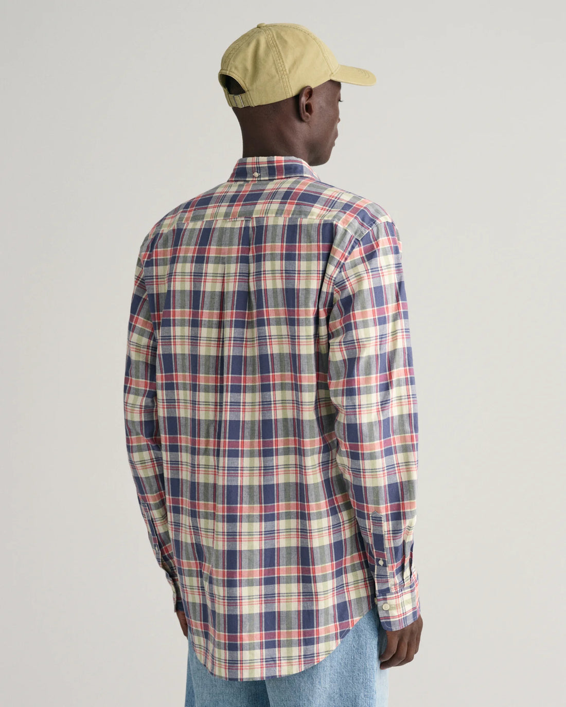 man facing the back wearing cap, denim pants, gant regular fit checkered cotton linen shirt in dusty blue sea