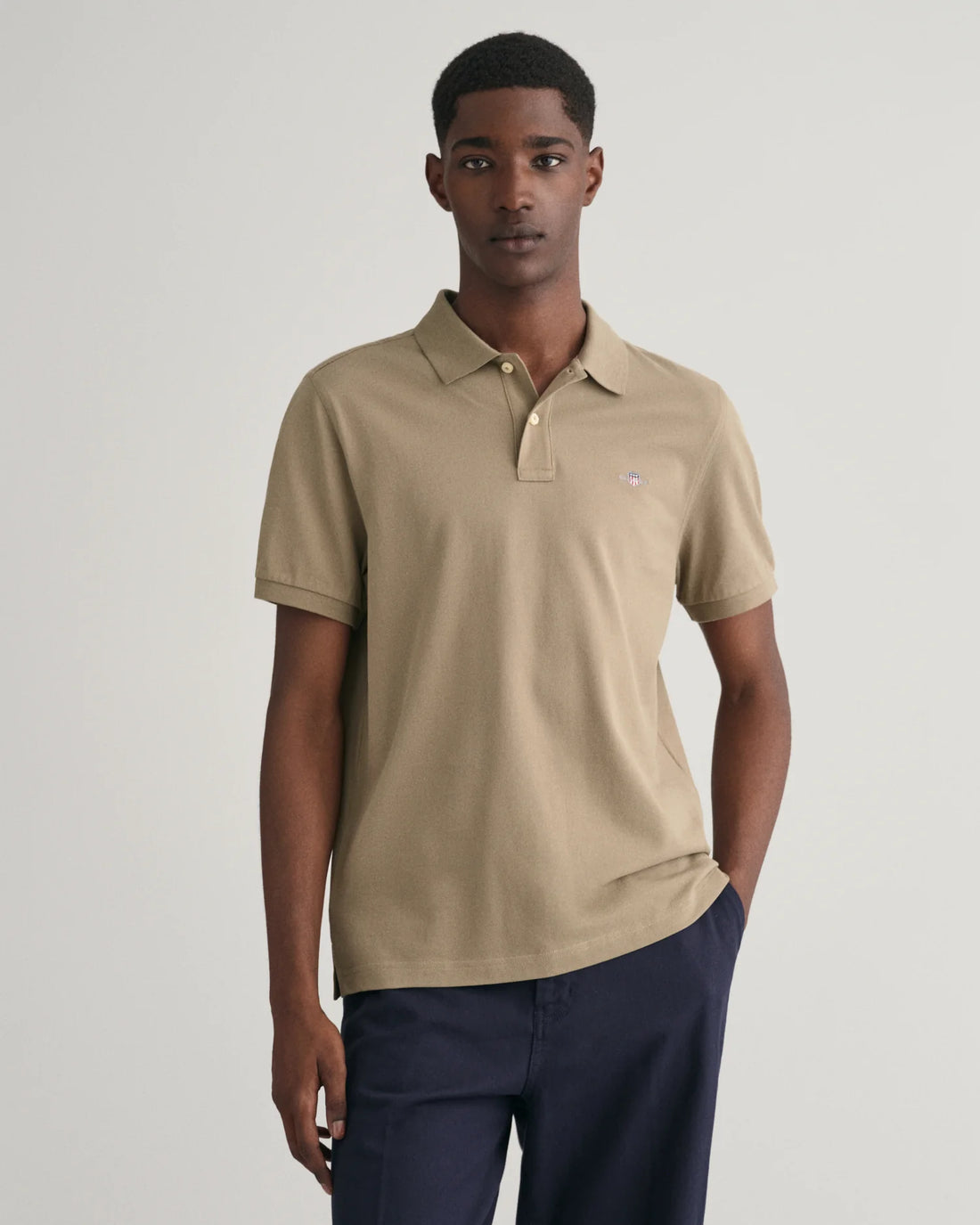man wearing gant regular fit shield pique polo shirt in dried clay, pants