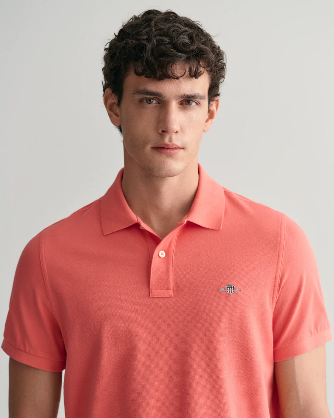 man standing wearing gant regular fit shield pique polo shirt in sunset pink