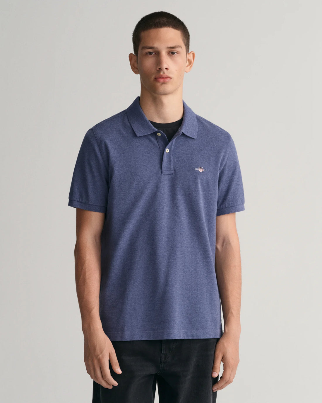 man wearing gant regular fit shield pique polo shirt in blue melange, black pants