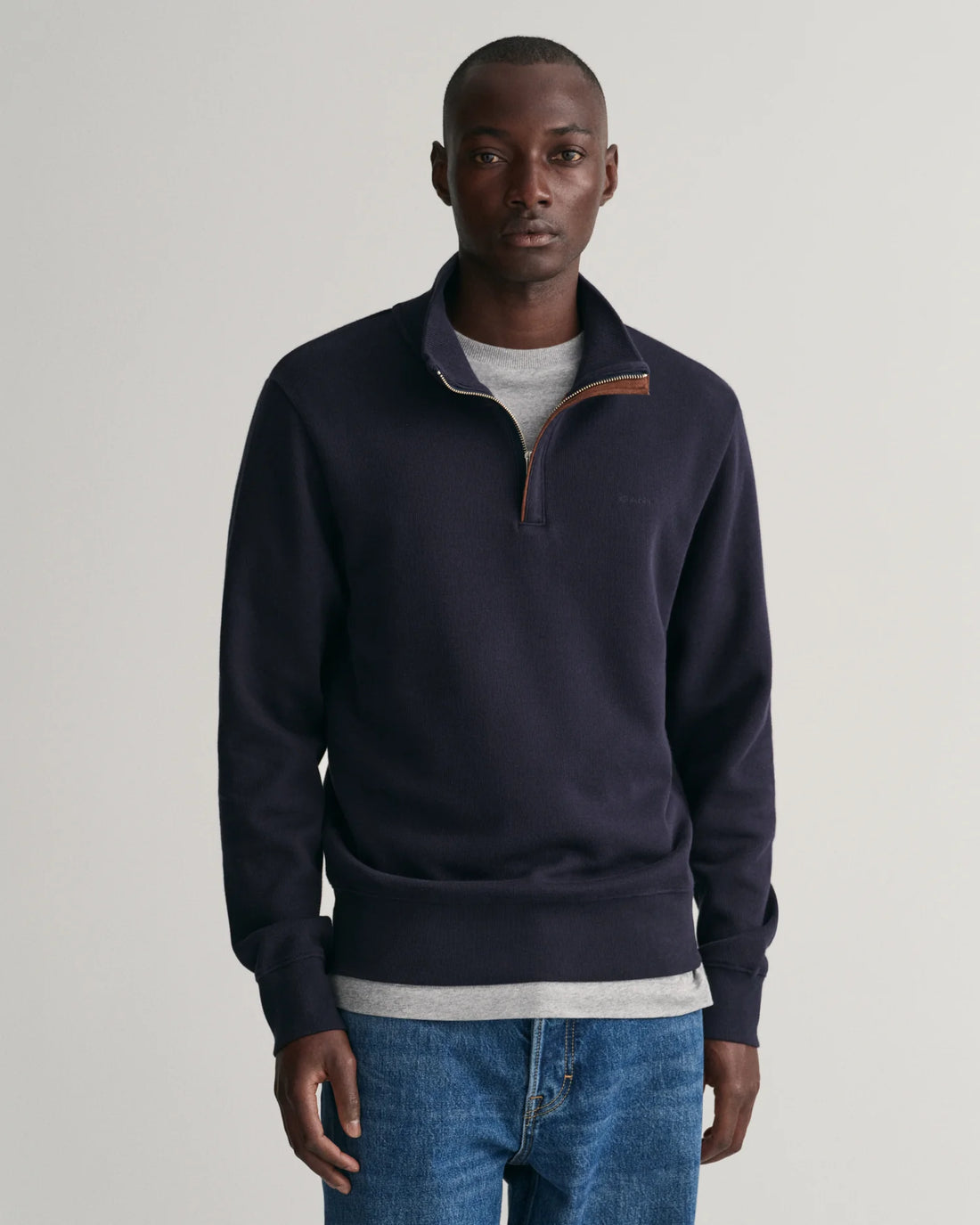 man wearing gant sacker rib half zip sweatshirt in evening blue, denim pants