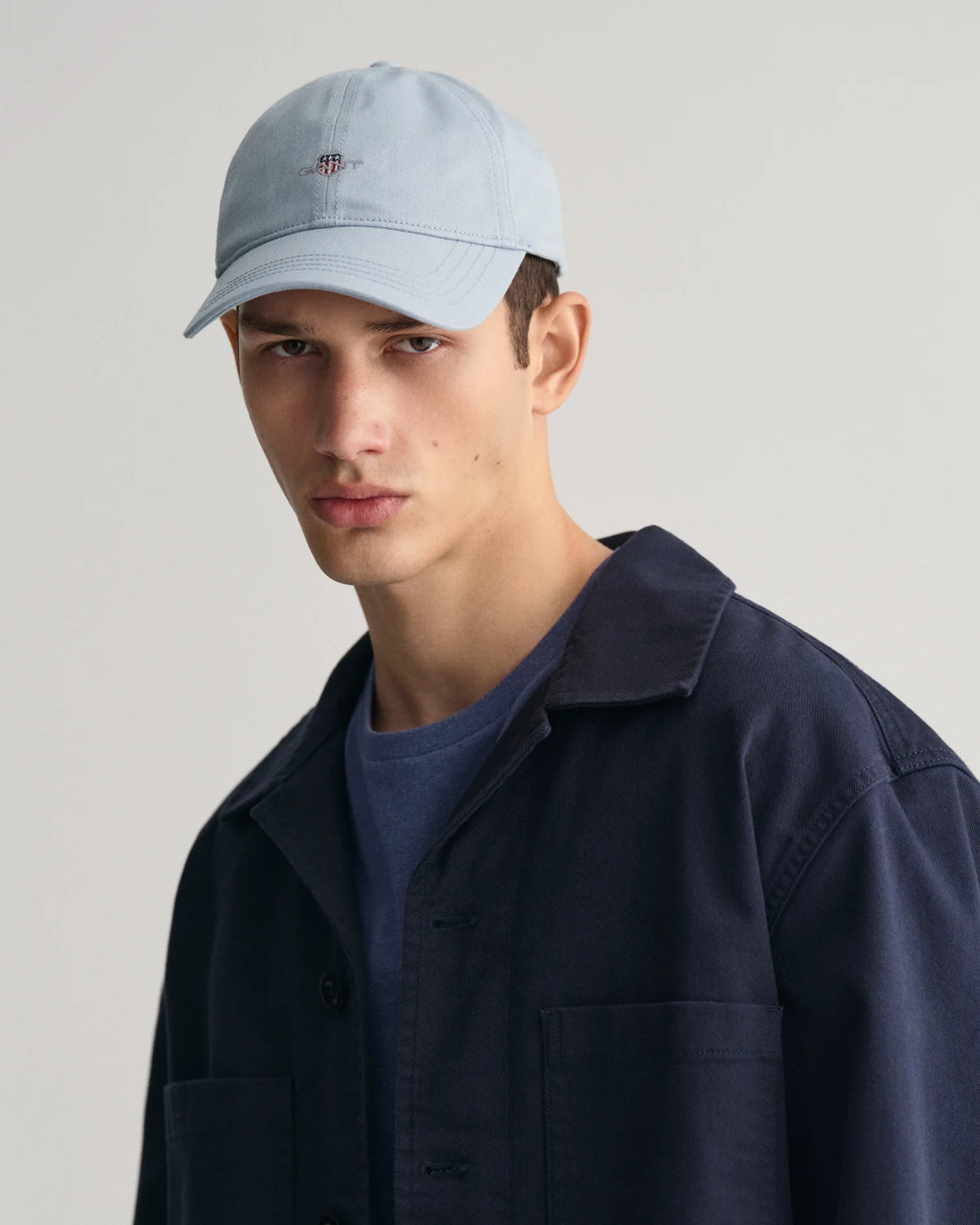 man wearing gant shield cap in dove blue, blue shirt and navy blue denim jacket