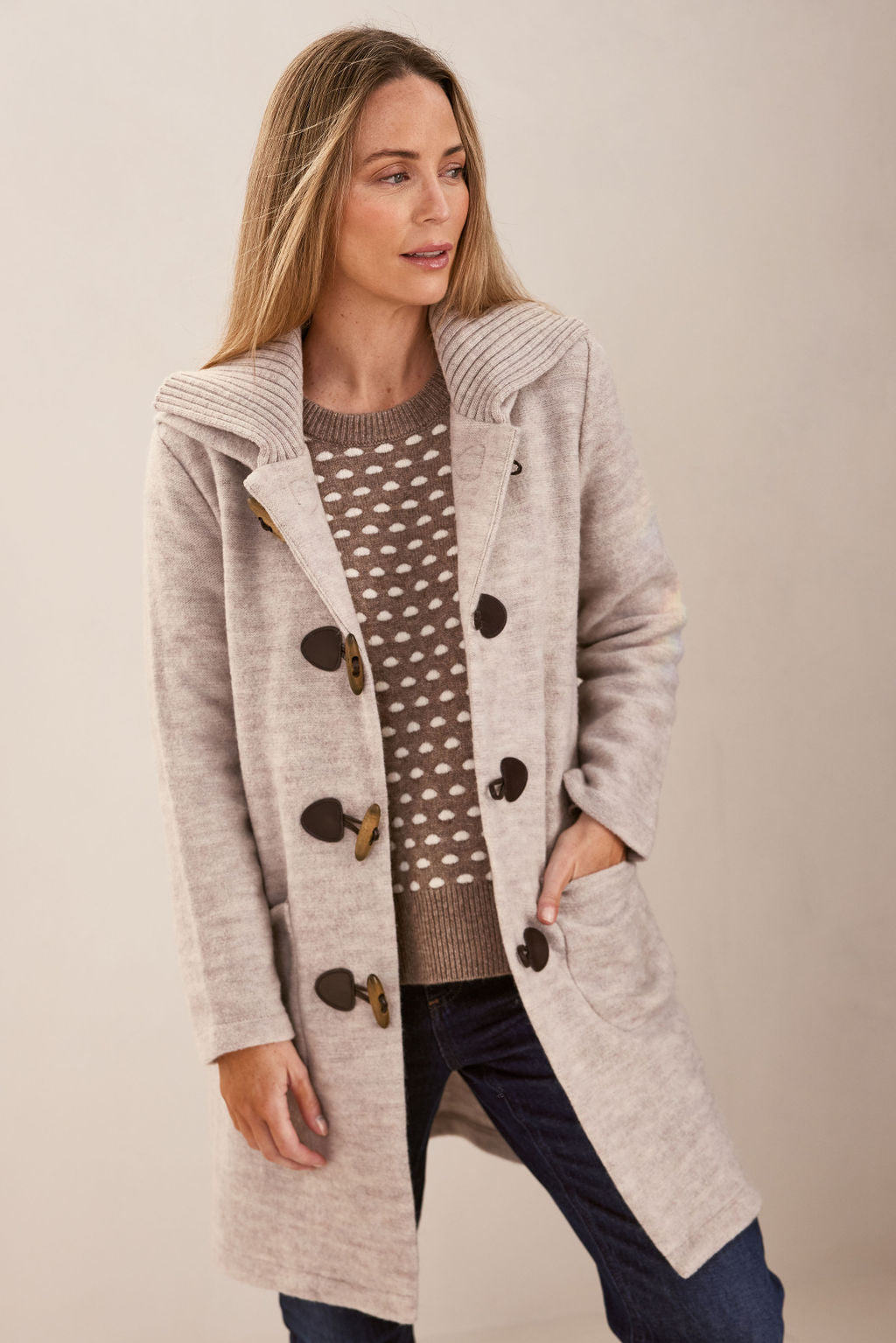 Woman wearing polka dot jumper, dark denim pants, and Wool Duffle Coat in Natural