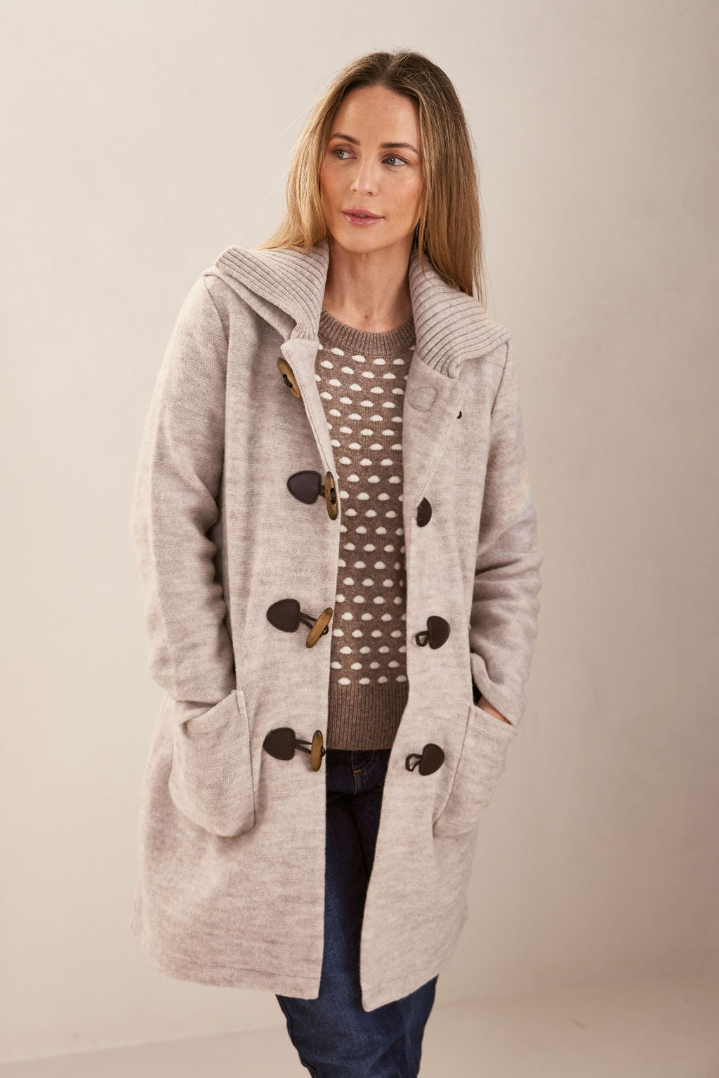 Woman wearing polka dot jumper, dark denim pants, and Wool Duffle Coat in Natural