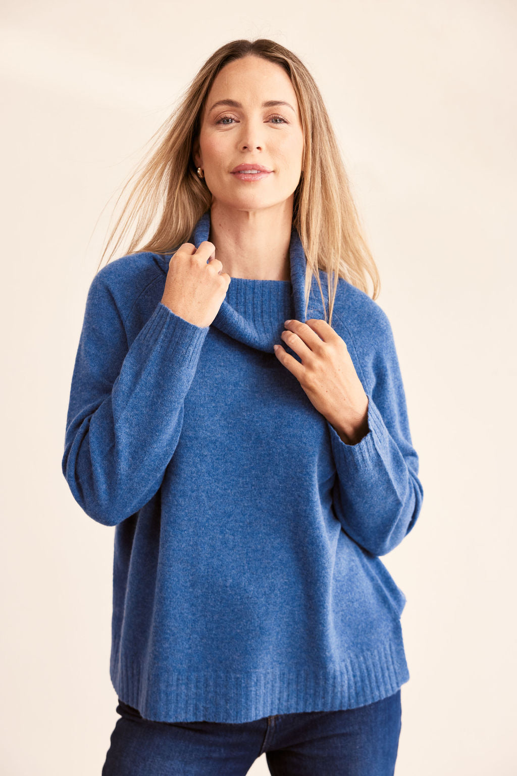 woman wearing 100% Merino Roll Neck Sweater - Denim and dark denim pants