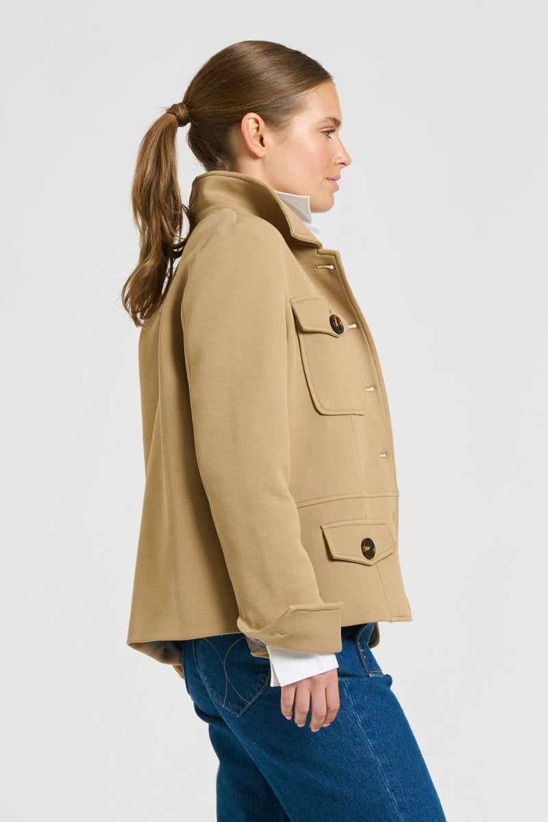 Woman facing the side wearing white long sleeve louse, blue denim pants and Hemming Scuba Jacket - Caramel