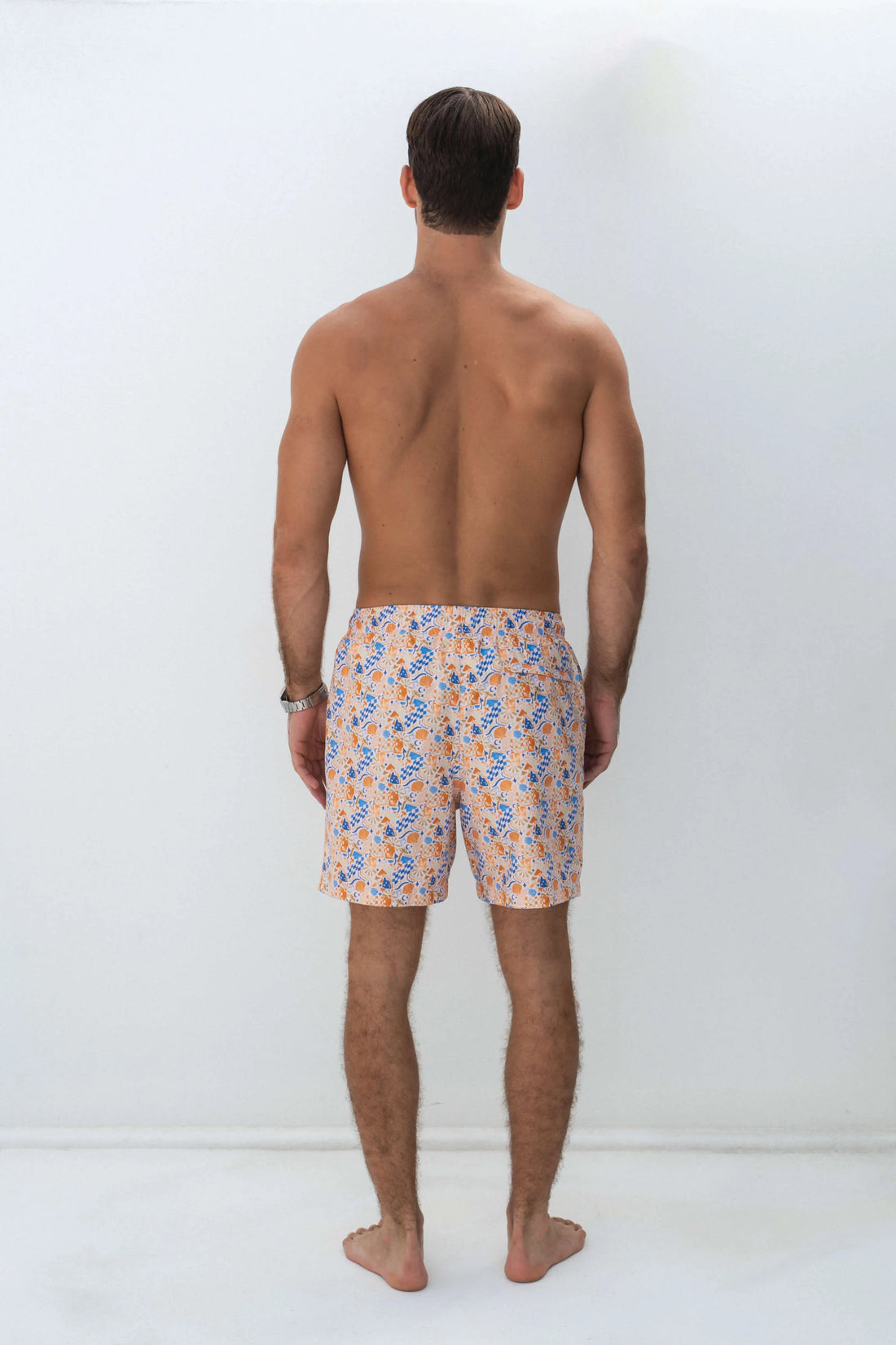 man facing the back wearing shore club swim means swim short in yacht rock design