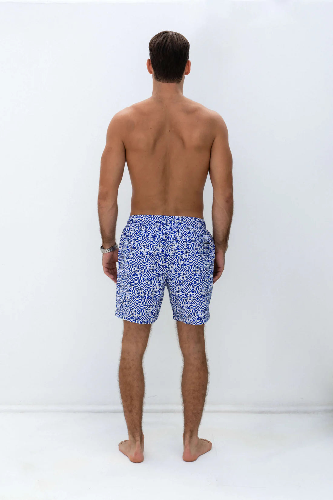 Man facing the back wearing shore club swim mens swim short in mediterranean sun design
